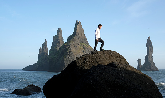 Man standing on a rock at Reynisfjara Black Beach, Iceland, with wind in his hair