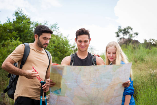 istock Group of young backpackers hikers hiking with backpacks looking map on mountain. Group of traveler with backpack walking on mountain forest trail 1336850113