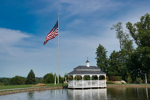 View of a Pond and Gazebo With an America Flag on a Beautiful Day