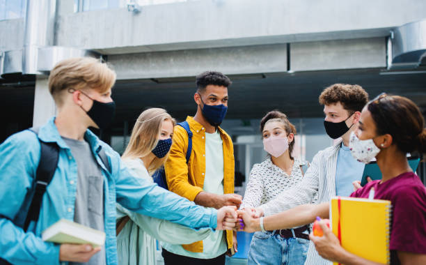 istock University students standing and greeting outdoors, coronavirus and back to normal concept. 1336859478