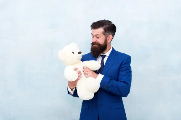 Photo of Fabulous gift for little ones. Bearded man hold teddy bear. Businessman with toy gift blue background. Happy boxing day. Cuddly soft present. Gift shop or store. Shopping for gift, copy space