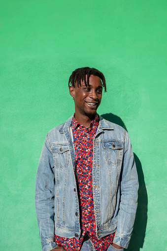 Portrait of young african man smiling on green colored background.
