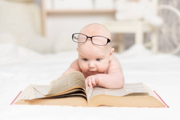 istock baby reading a book or looking at it in the nursery, learning and development concept 1336860950
