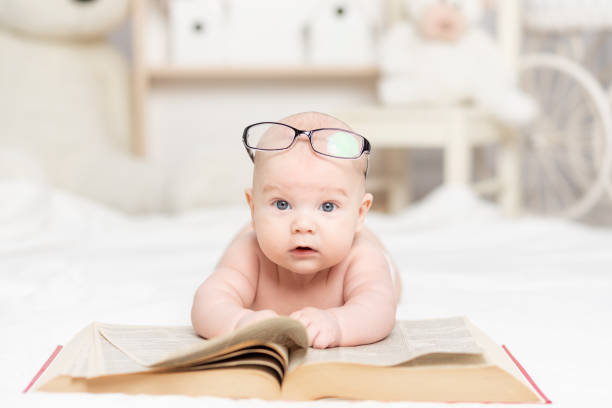 istock baby reading a book or looking at it in the nursery, learning and development concept 1336860957