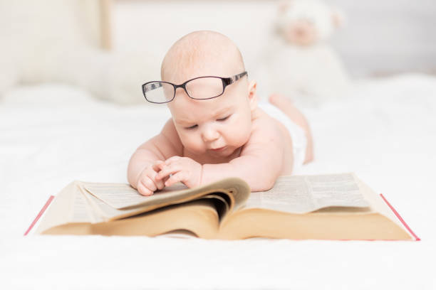 istock baby reading a book or looking at it in the nursery, learning and development concept 1336860979