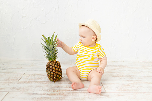 baby with pineapple on white background, travel and summer vacation concept, copy space