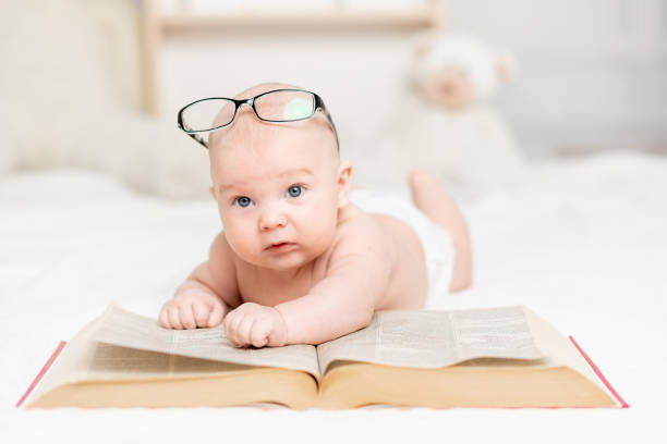 istock baby reading a book or looking at it in the nursery, learning and development concept 1336862649