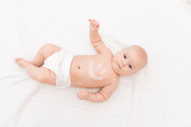 istock baby with a smile on his stomach on a light background 1336862686