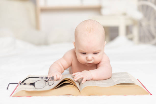 istock baby reading a book or looking at it in the nursery, learning and development concept 1336862700