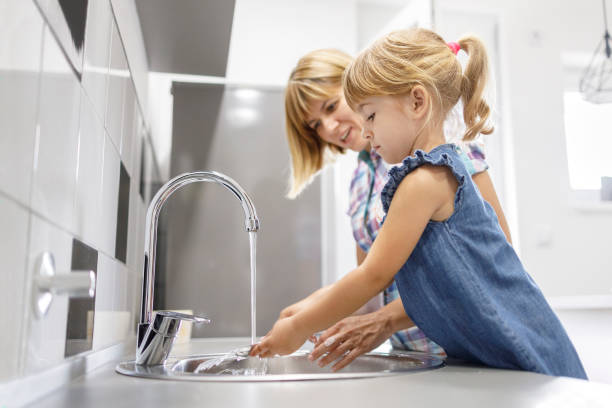 istock Child washing dishes and mother looking at her 1336866428