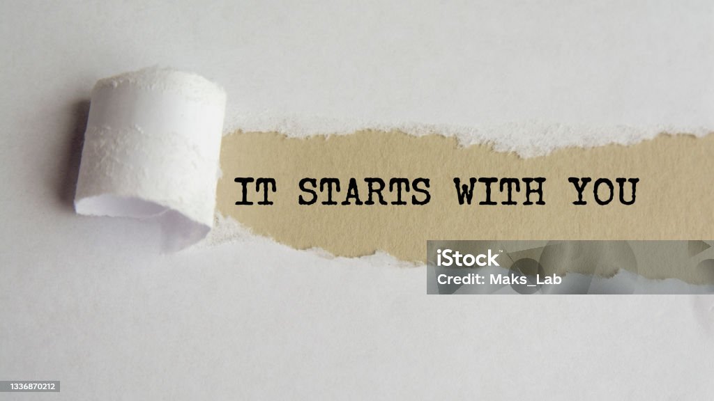 IT STARTS WITH YOU. words. text on grey paper on torn paper background IT STARTS WITH YOU. words. text on grey paper on torn paper background. Responsibility Stock Photo