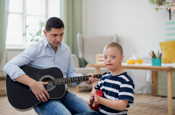 istock Cheerful down syndrome boy with father playing musical instruments, laughing. 1336870668