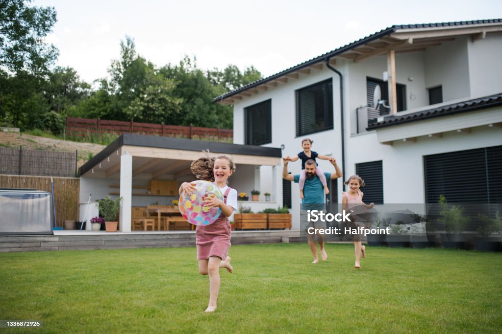 Father with three daughters playing outdoors in the backyard, running. A father with three daughters playing outdoors in the backyard, running. Family Stock Photo