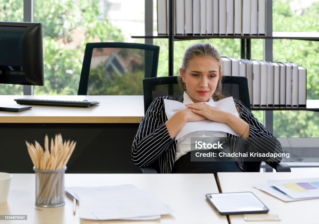 Sad Caucasian businesswoman losing job, sitting on the table in the office. The concept of unemployed, sadness, depressed and human problems. Shock Stock Photo