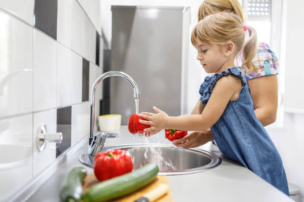 istock Mother and daughter washing vegetables 1336875275