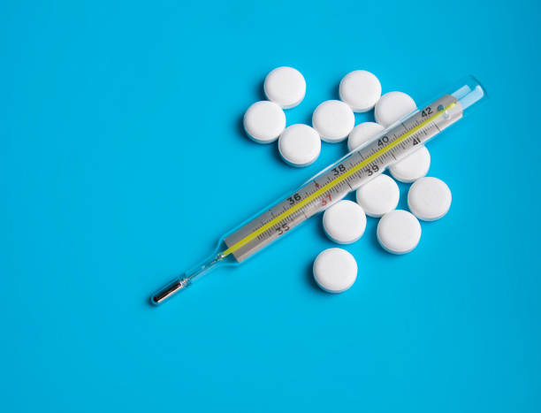 istock thermometer and white pills on the blue background 1336877761
