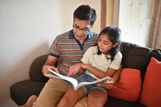 istock Girl sitting on father's lap and reading a book 1336878800