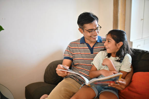 istock Girl sitting on father's lap and reading a book 1336878808