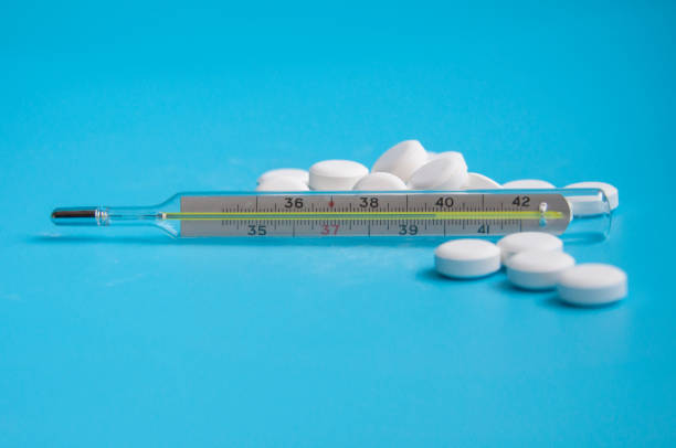 istock thermometer and white pills on the blue background 1336878937