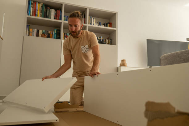 молодой человек расставляет плоскую мебель в своем новом доме. - furniture model kit home improvement wood стоковые фото и изображения