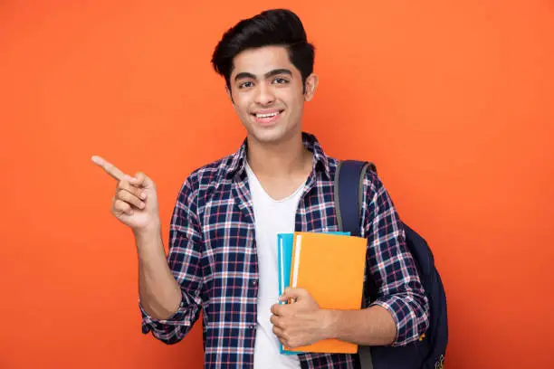 Photo of Male teenage student in orange background stock photo
