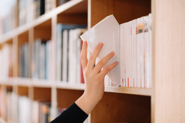 istock Girl hand picking a book on a library shelf 1336884653