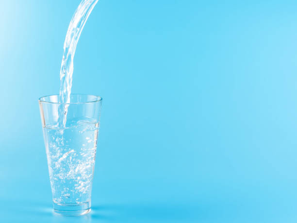 istock Glass with water aqua on blue background 1336885496
