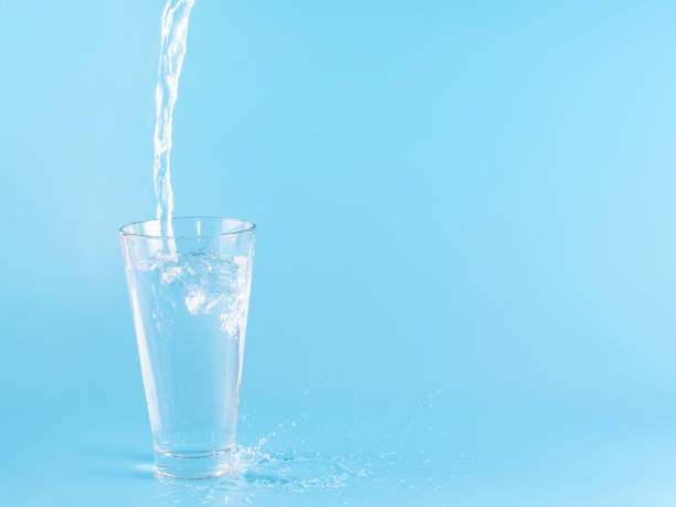 istock Glass with water aqua on blue background 1336885748