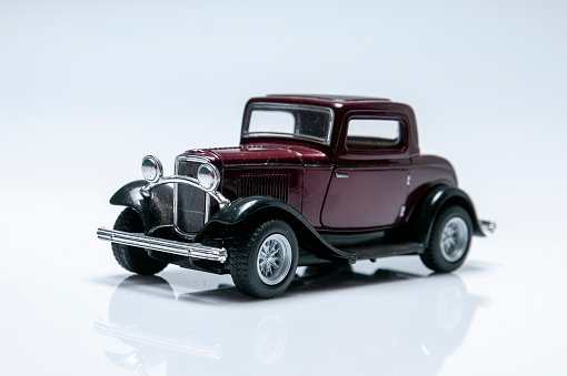 Metal model toy of a retro car stands on a wooden surface on a bright abstract background