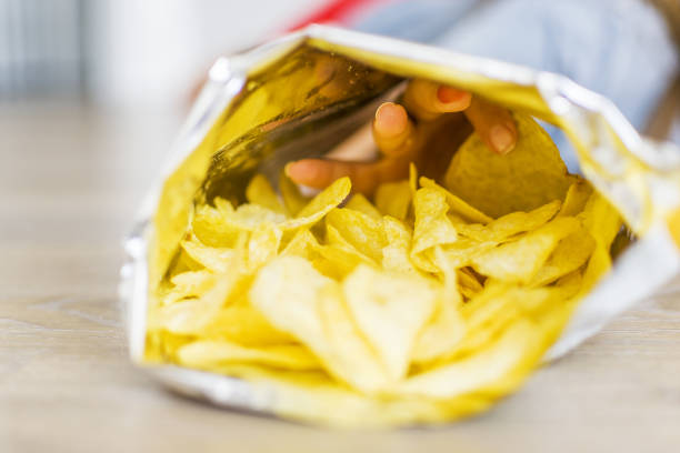 istock Little girl eating potato chips in a bag or package 1336891207