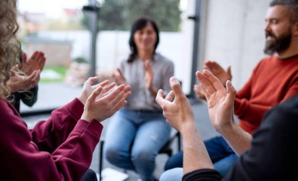 istock Men and women sitting in circle during group therapy, clapping. 1336891296