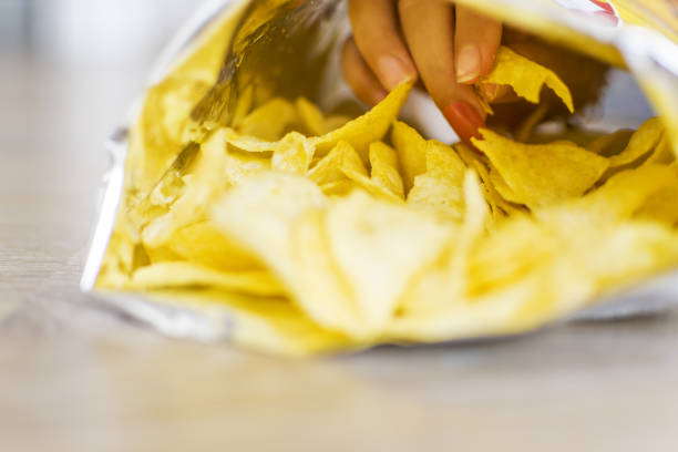 istock Little girl eating potato chips in a bag or package 1336891431