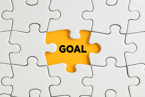 The word goal written on yellow missing puzzle piece. To discover goals concept.