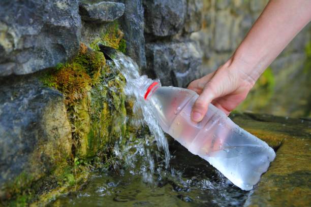 source of spring water bottle filling holding hand in Pyrenees mountain