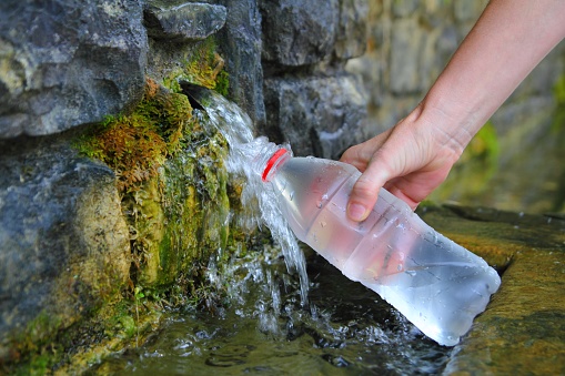 source of spring water bottle filling holding hand in Pyrenees mountain