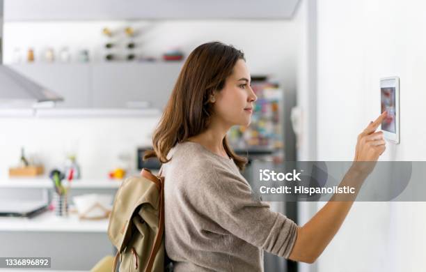 Woman Leaving Her House And Locking The Door Using A Home Automation System Stock Photo - Download Image Now