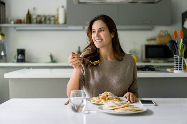 istock Happy woman eating dinner at home 1336896906