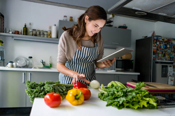 istock Happy woman cooking at home following an online tutorial 1336896914