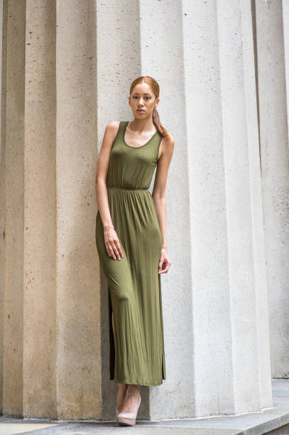 istock Young woman standing outdoors against column, relaxing 1336898023