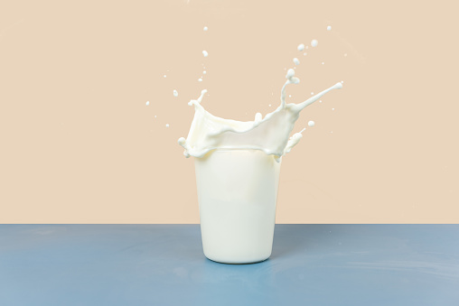 The splashing milk in the cup is against a yellow and gray background