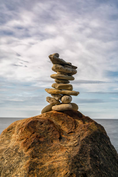 cairn rocheux méditatif au sommet d’un rocher avec une longue exposition à l’océan et au ciel en arrière-plan - long exposure rock cloud sky photos et images de collection