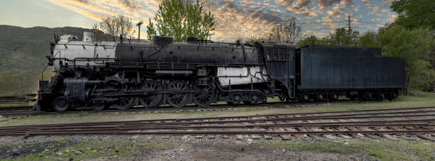 istock Old black railroad train on tracks at sunset 1336905878