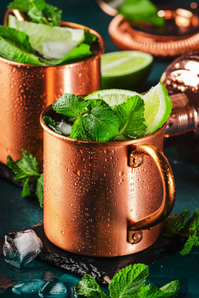 Moscow mule cocktail in copper mug with lime, ice, ginger beer, vodka and mint. Deep blue background and bar tools Moscow mule cocktail in copper mug with lime, ice, ginger beer, vodka and mint. Deep blue background and bar tools mint julep photos stock pictures, royalty-free photos & images