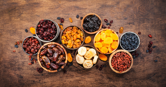 Dried fruits bowl. Healthy food snack: sun dried organic mix of apricots, figs, raisins, dates and other on wooden table, top view