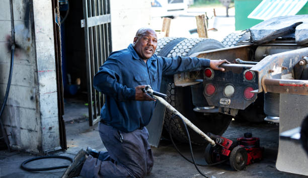 istock African-American man repairing semi-truck, using jack 1336909959