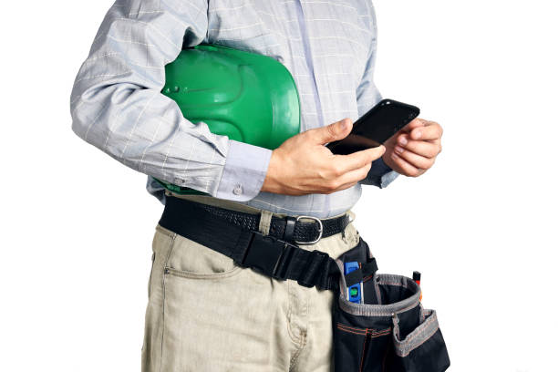 istock Builder with tools and hard hat holds smartphone in his hands 1336911095