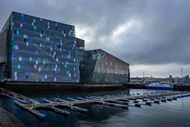 REYKJAVIK, ICELAND - July 5, 2021: Harpa Concert hall, on cloudy, stormy day. \nThe building has a distinctive, colourful glass facade, which is inspired by icelandic basalt rocky landscape.