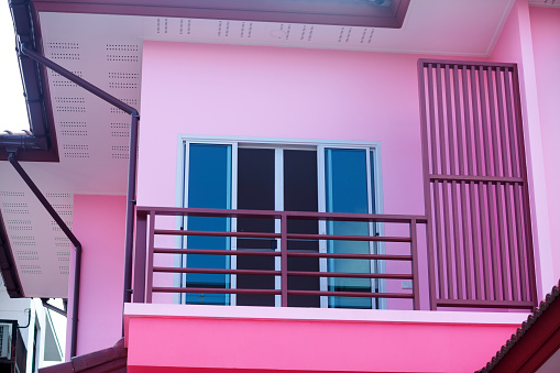 Window with blue shutters of pink colored house in Bangkok Chatuchak