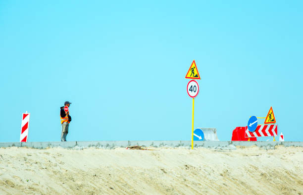 trabajador sosteniendo una señal de alto durante la construcción de la carretera. construcción de carreteras en la carretera. - n64 fotografías e imágenes de stock