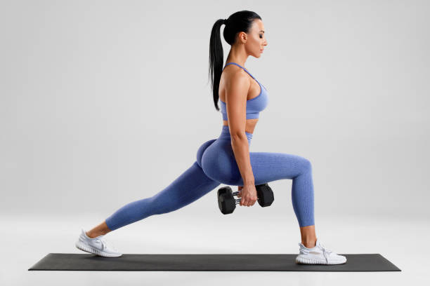 istock Fitness woman doing lunges exercises for leg muscle workout training. Active girl doing front forward one leg step lunge exercise 1336925574